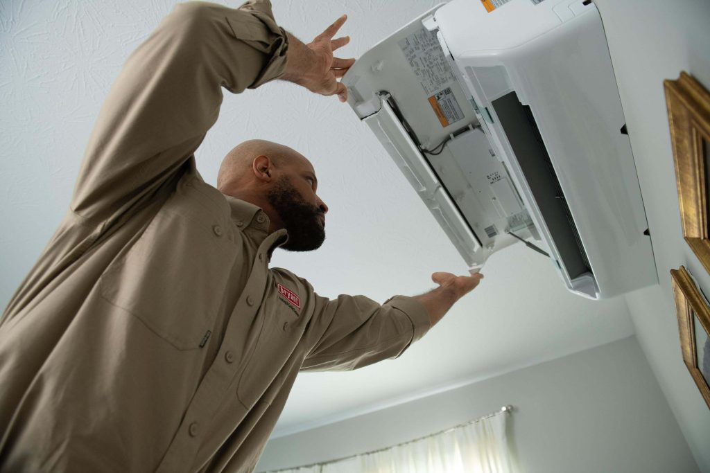 A technician in repairs an air conditioner, demonstrating AC repair services in action.