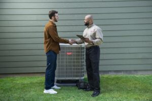 A technician shakes hands with a homeowner in front of a new Bryant AC unit.