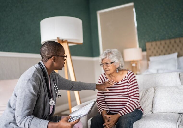 How Your HVAC Equipment Protects Against Viruses. Doctor talking to a senior woman in the bedroom.