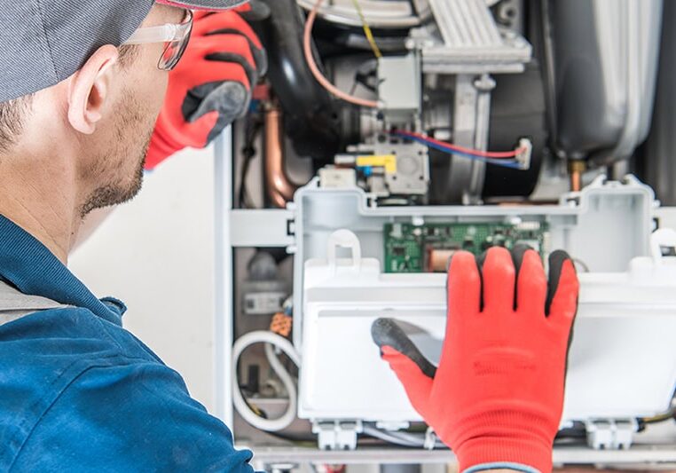 Schedule Your Annual Furnace Inspection Now. A technician inspecting a furnace.